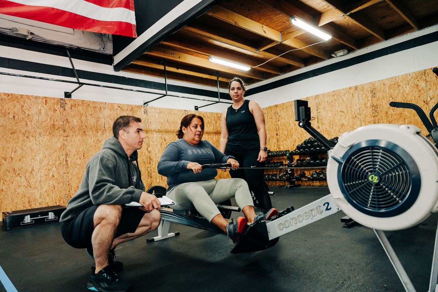 Coaches working with members on the rower